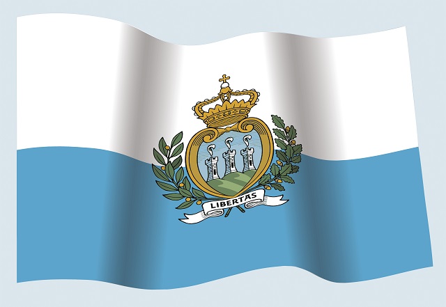サンマリノの国旗。白はティターノ山の雪と純粋さ、水色は空とアドリア海を表しているといわれる。 中央の国章は、盾の中に3つの丘と3つの塔。国の標語であるラテン語「LIBERTAS（自由）」の文字も。