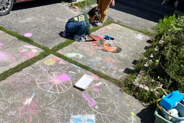筑紫野筑前（福岡）の子どもたち。親たちの活動のそばで、いつの間にか大きな地面キャンパスにお絵描き。子どもたちの「やってみたい！」が尊重される、安心できる居場所。