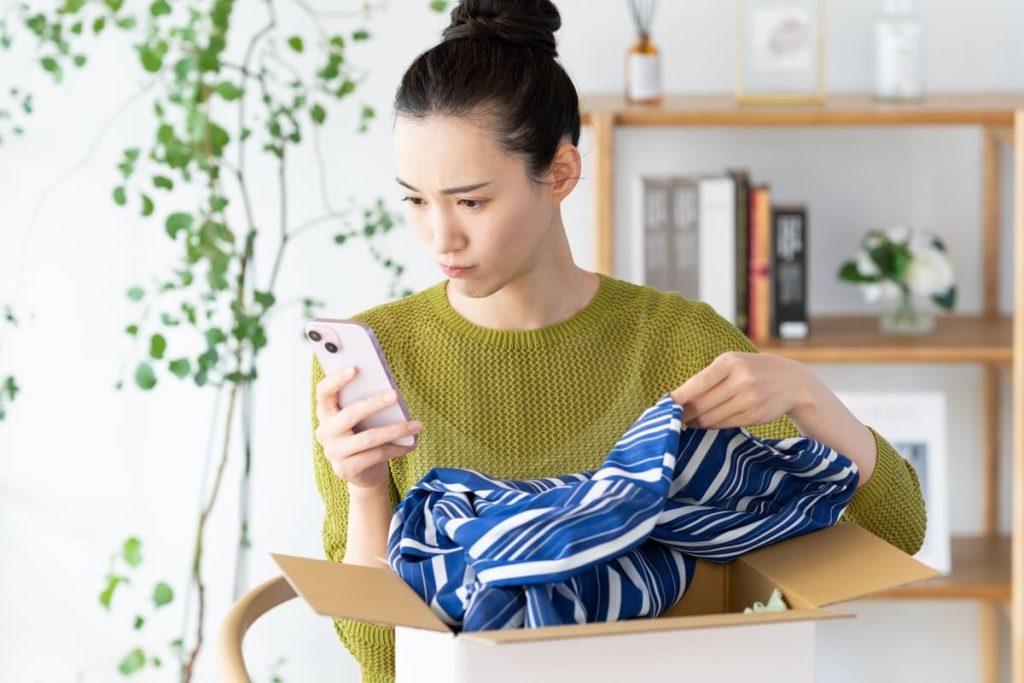 荷物とスマホを見ながら困っている女性